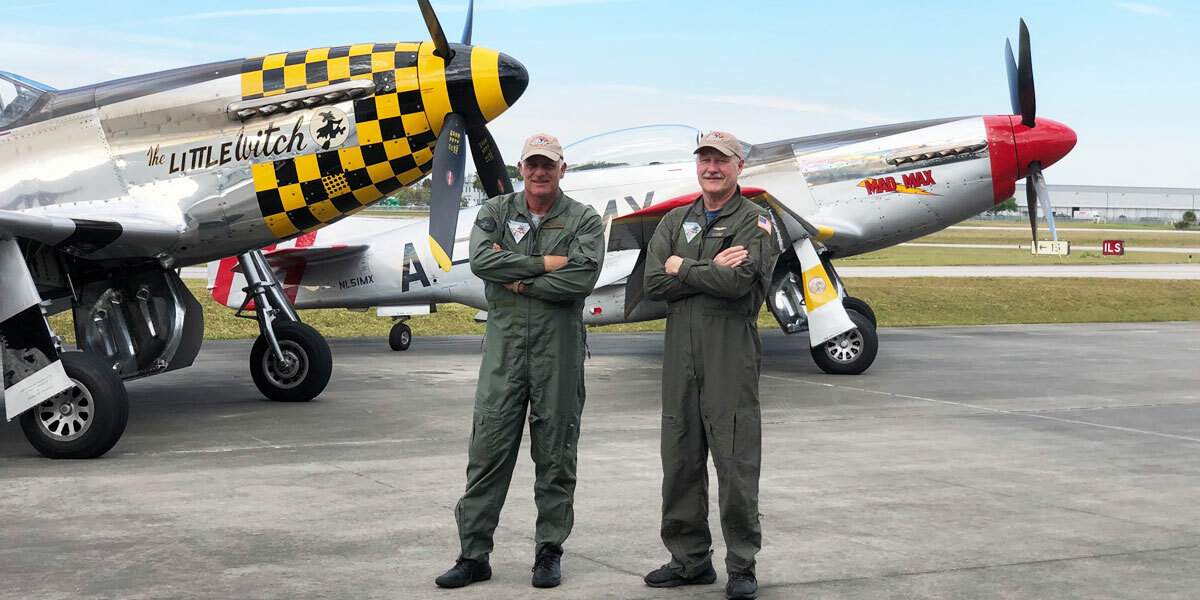 Team members standing in front of two P-51 planes