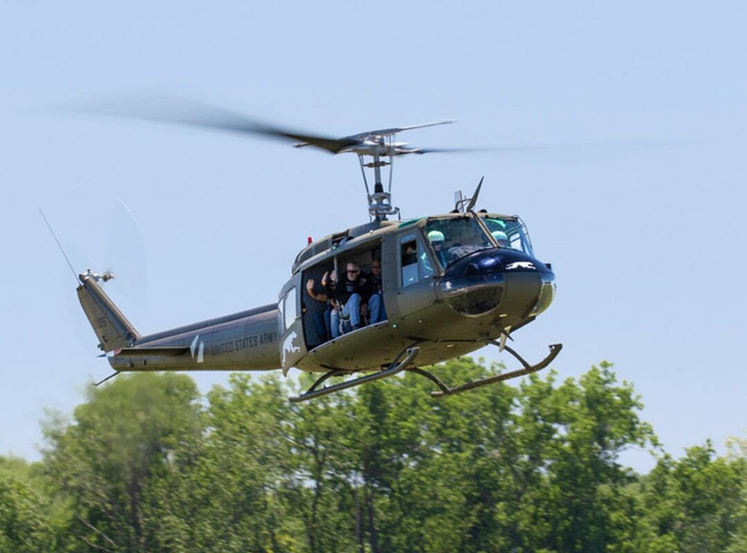 CAS_2025_HueyFlights_min UH-1 Huey in flight - just above the ground with trees in the background.