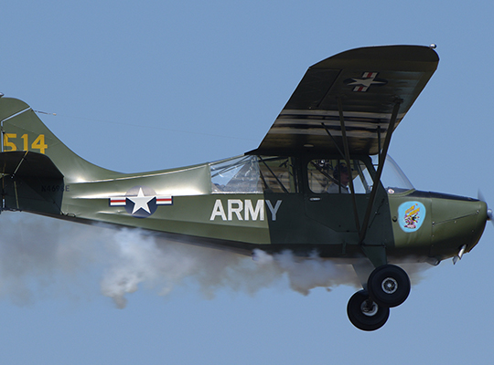 Aeronca L-16 liaison aircraft in flight against clear blue sky