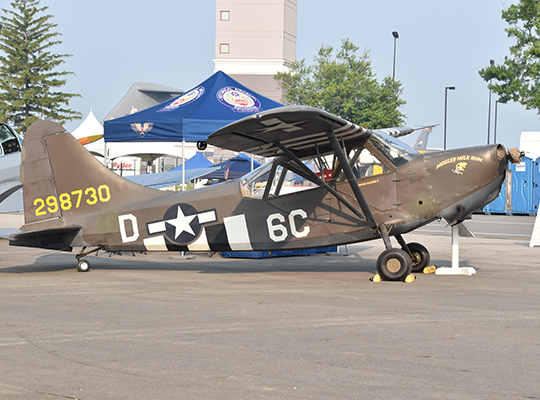 Stinson L-5 liaison aircraft parked on tarmac with military markings and canopy open