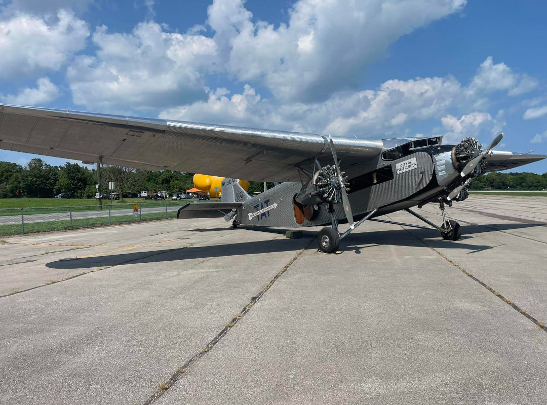 1928 Ford Tri-Motor “City of Wichita,” a rare historic aircraft with three radial engines and corrugated metal body, parked on an airport tarmac under a partly cloudy sky; one of only four airworthy examples remaining out of 199 built.